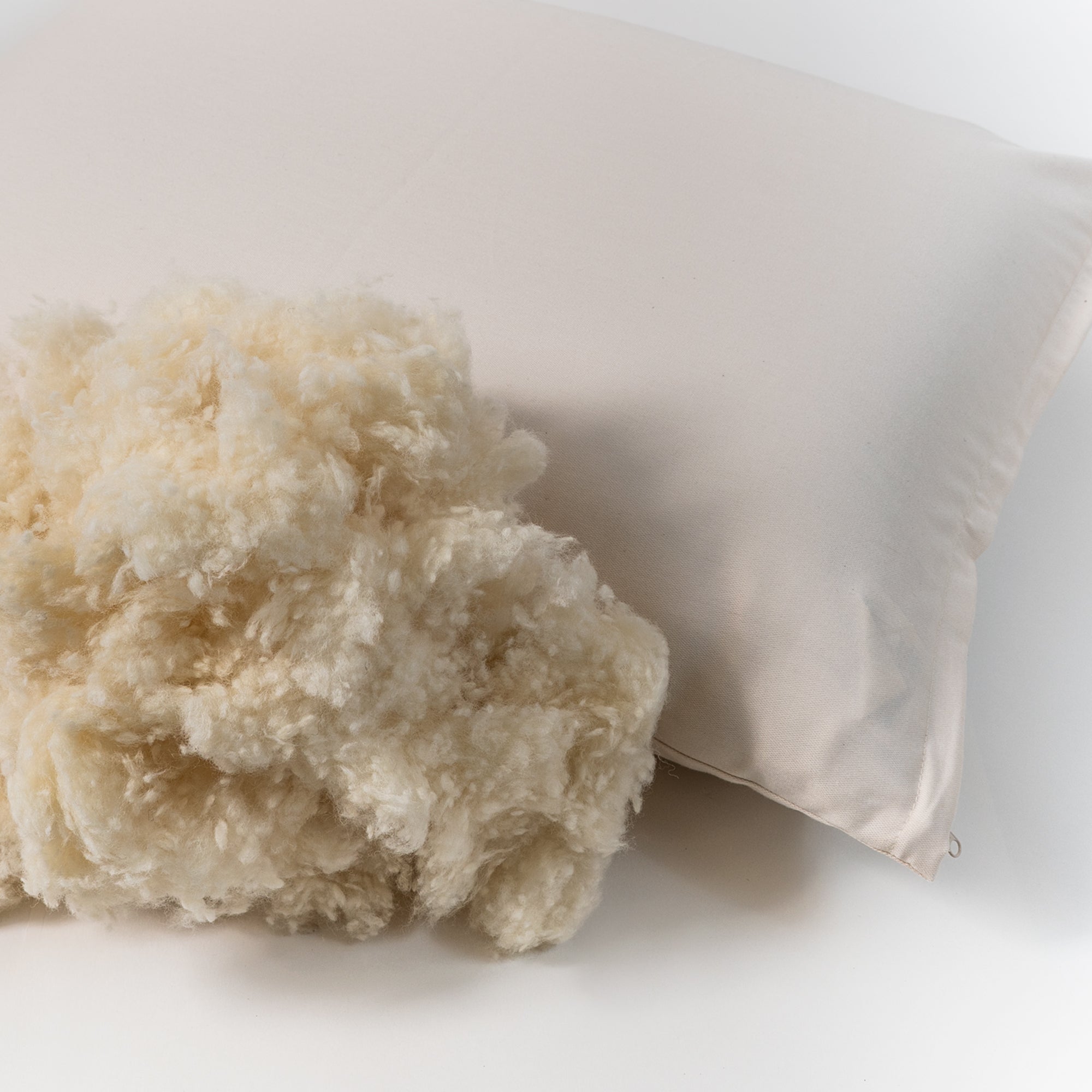 Natural wooly bolas pillow. Covered in a sateen fabric of organic cotton fibers.
